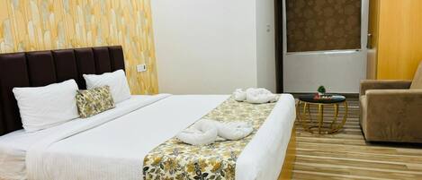 A hotel room with a large bed, a wooden headboard, a small round table with a plant, and a brown armchair.