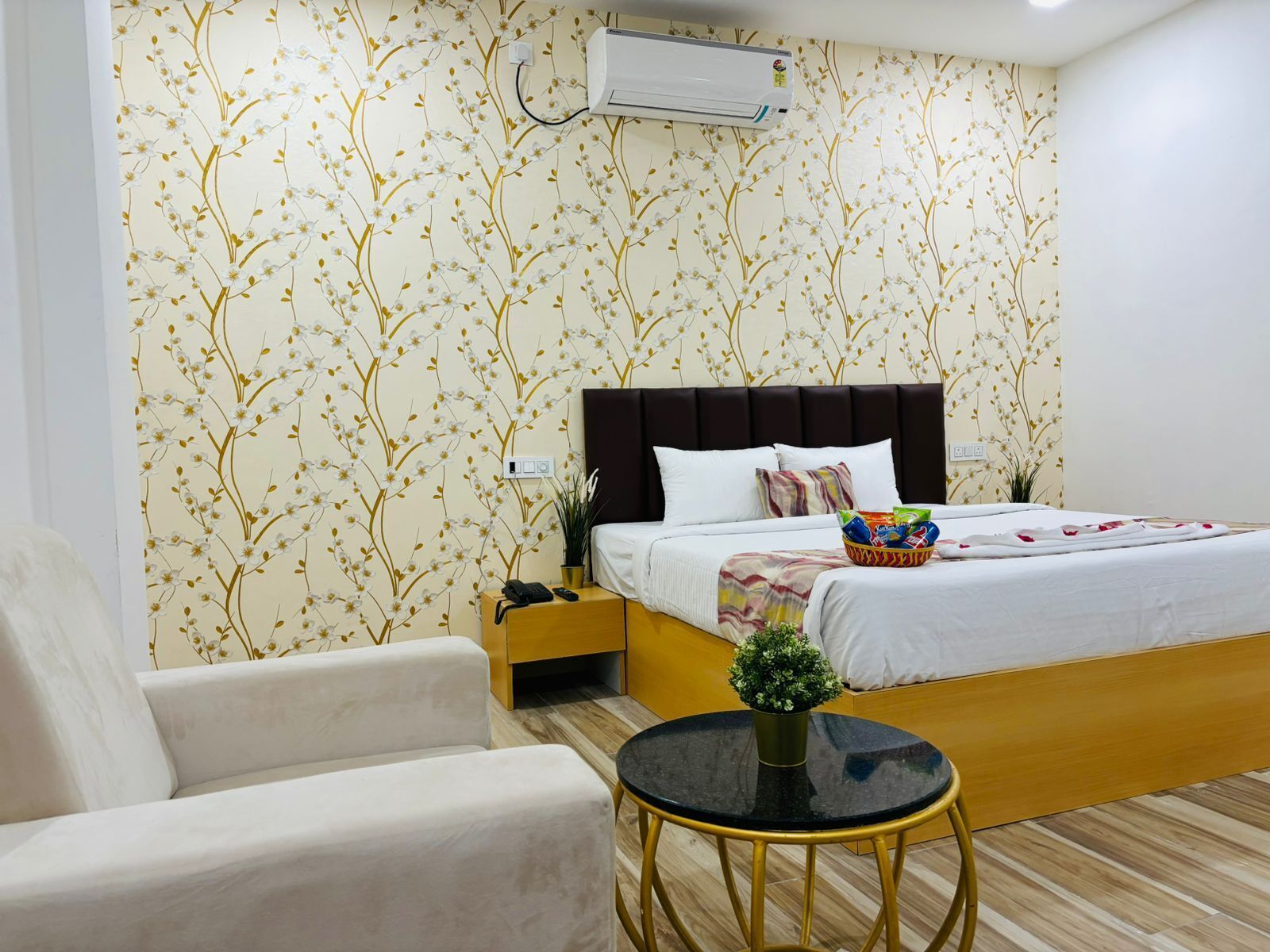 A hotel room with a bed, bedside table, chair, and a small round table.