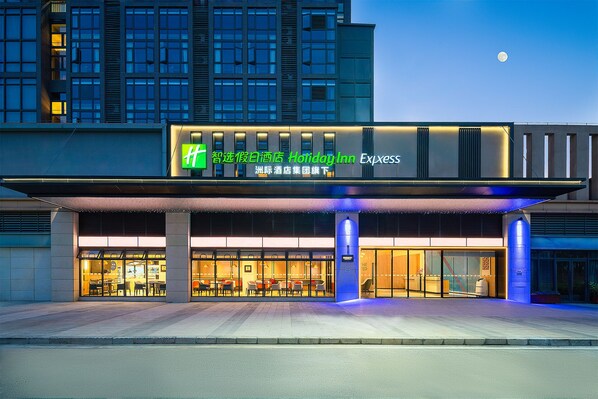 A Holiday Inn Express hotel with a modern facade, large windows, and a covered entrance area. - Holiday Inn Express Guangzhou University Town by IHG (Guangzhou)