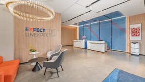 A modern reception area with a wooden wall, a reception desk, and a seating area with a round table and chairs. - Holiday Inn Express Guangzhou University Town by IHG (Guangzhou)