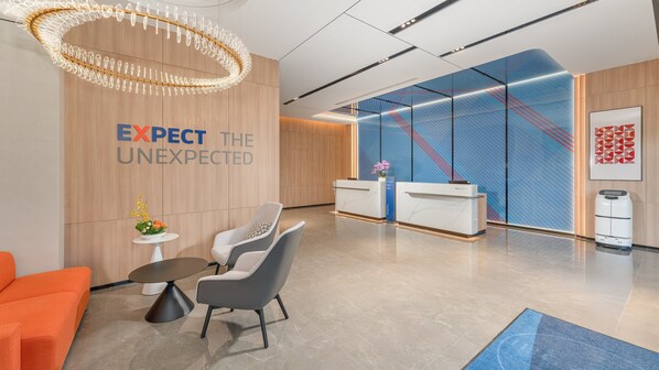 A modern reception area with a wooden wall, a reception desk, and a seating area with a round table and chairs.
