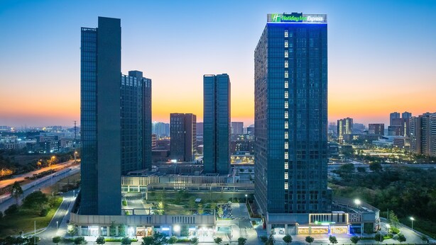 A high-rise hotel with a prominent Holiday Inn Express sign, surrounded by other tall buildings and a well-lit urban environment. - Holiday Inn Express Guangzhou University Town by IHG (Guangzhou)