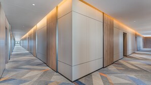 A long, narrow hallway with a patterned carpet and wooden panel walls. - Holiday Inn Express Guangzhou University Town by IHG (Guangzhou)