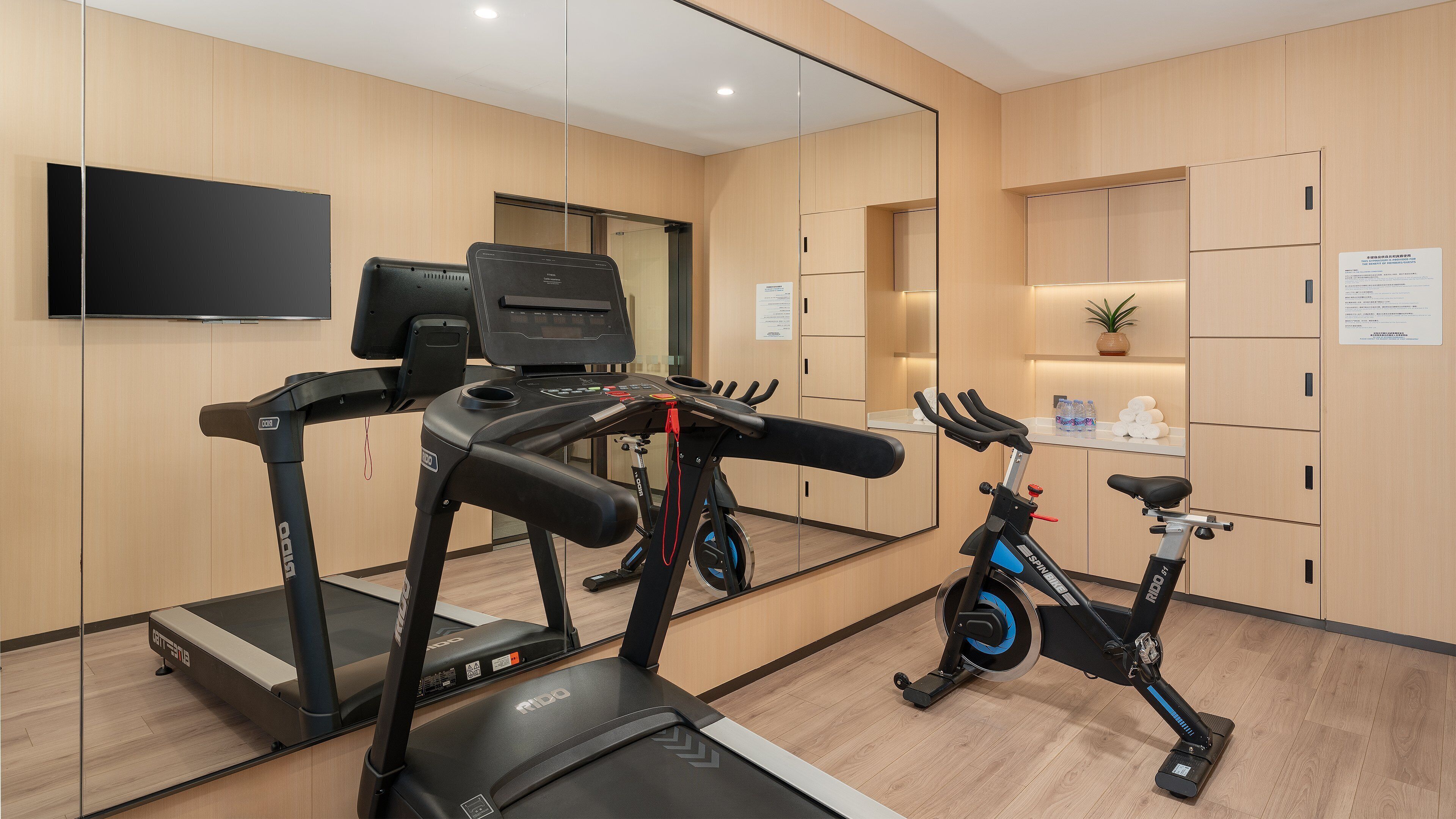 Ein Fitnessstudio mit Laufbändern, Ergometer und einer Spiegelwand.
