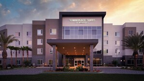 A modern hotel with a prominent entrance, multiple floors, and a landscaped courtyard with palm trees.