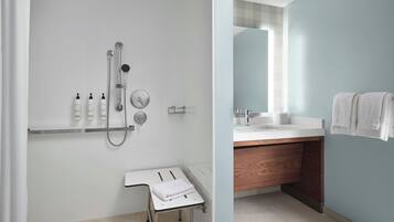 A modern bathroom with a shower, a vanity with a mirror, and a towel rack.
