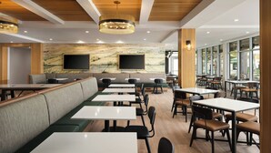 A modern dining area with booths and tables, wooden ceiling, and large windows.