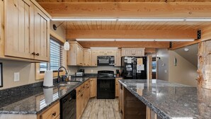 Una cocina con armarios de madera, encimeras de granito, horno empotrado y refrigerador.