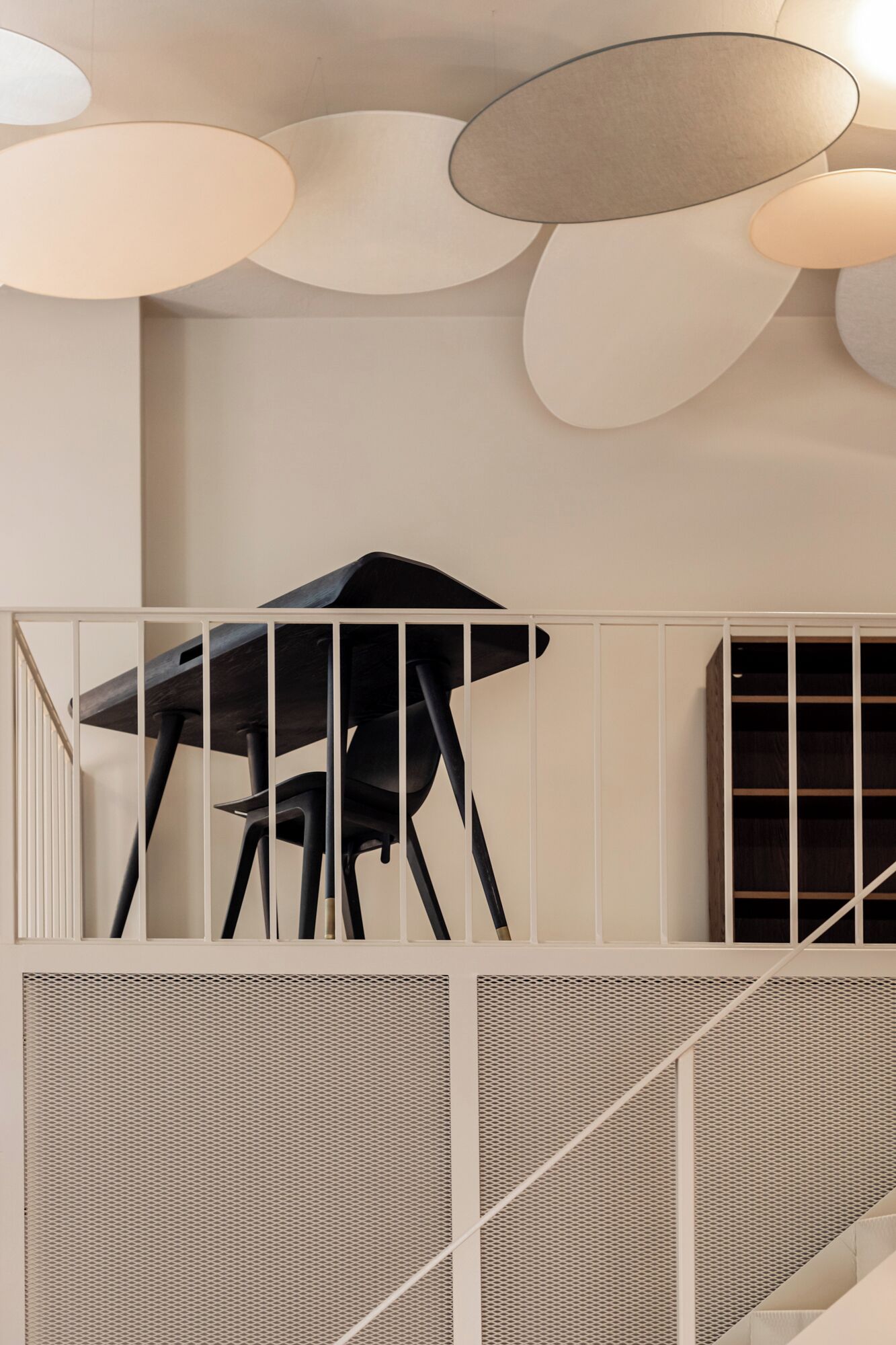 A modern interior with a staircase, a black chair, and a ceiling with circular light fixtures.