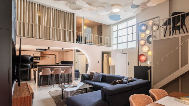 Un amplio loft con una cocina moderna, una zona de estar acogedora con un sofá seccional y un comedor.