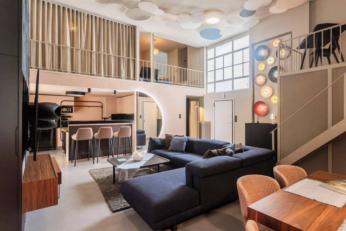 A spacious loft apartment with a modern kitchen, a cozy living area with a sectional sofa, and a dining area.