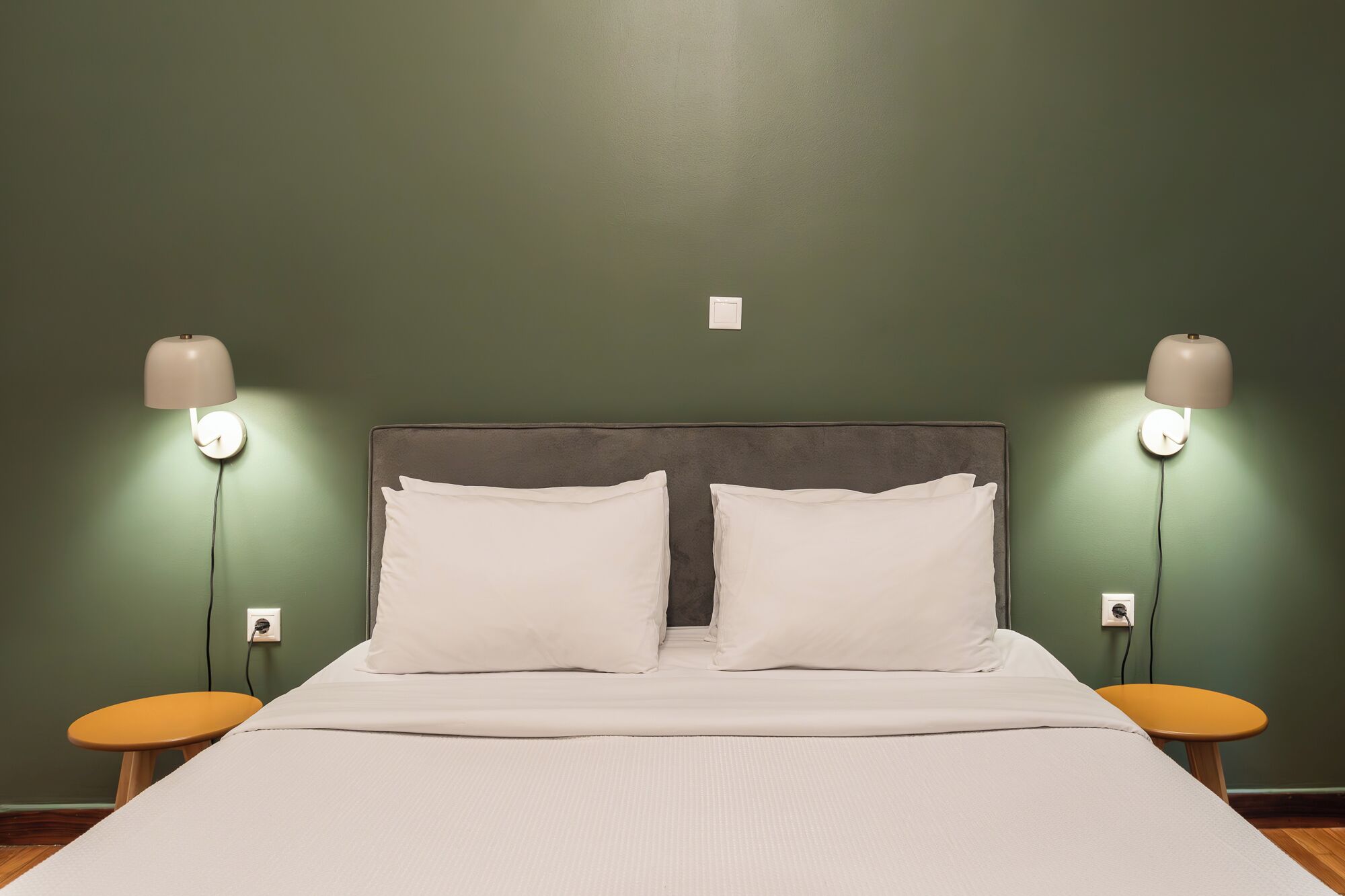 A neatly made bed with two pillows, a headboard, and two bedside lamps on either side.