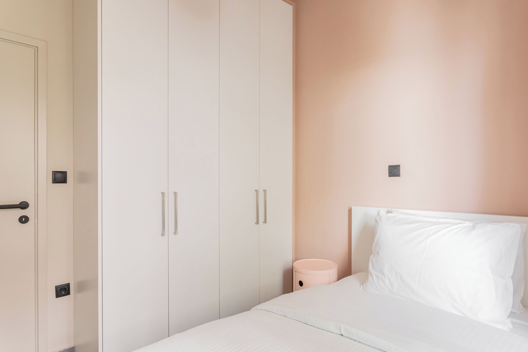 Een slaapkamer met een bed, een kledingkast en een nachtkastje.