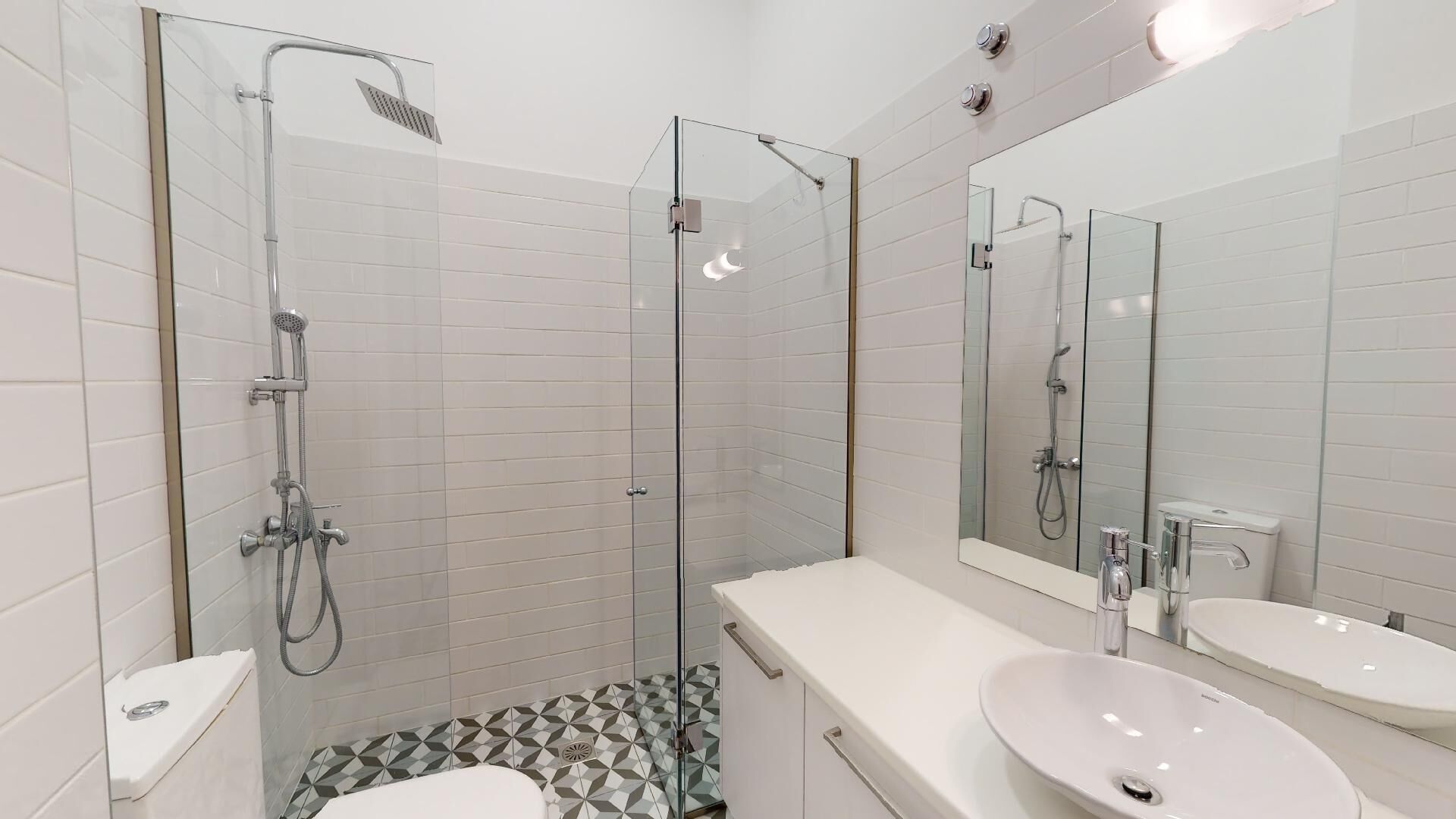 A modern bathroom with a glass-enclosed shower, a white sink, and a toilet.