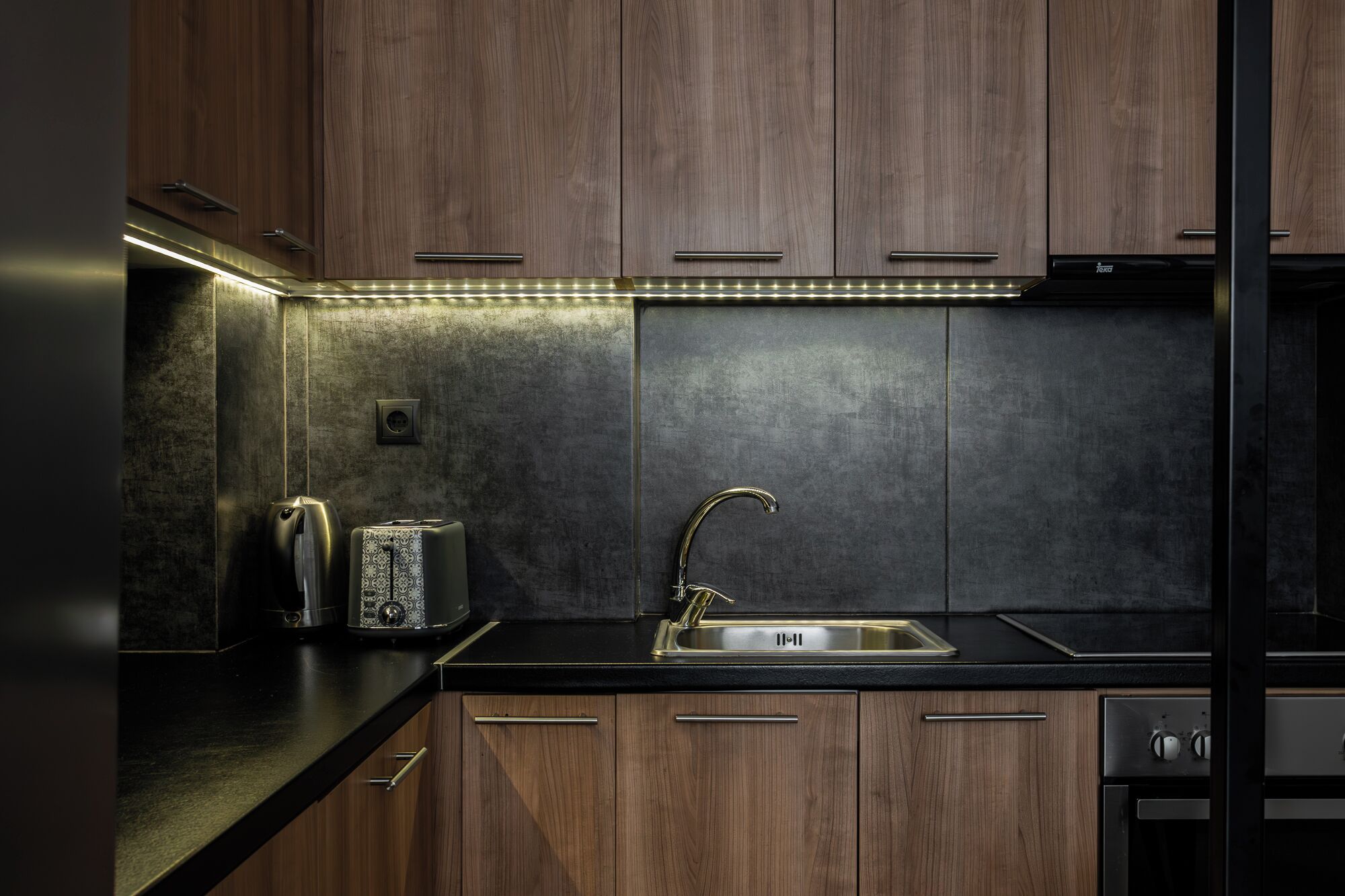 Une cuisine moderne avec des meubles en bois, un évier en acier inoxydable et un four encastré.