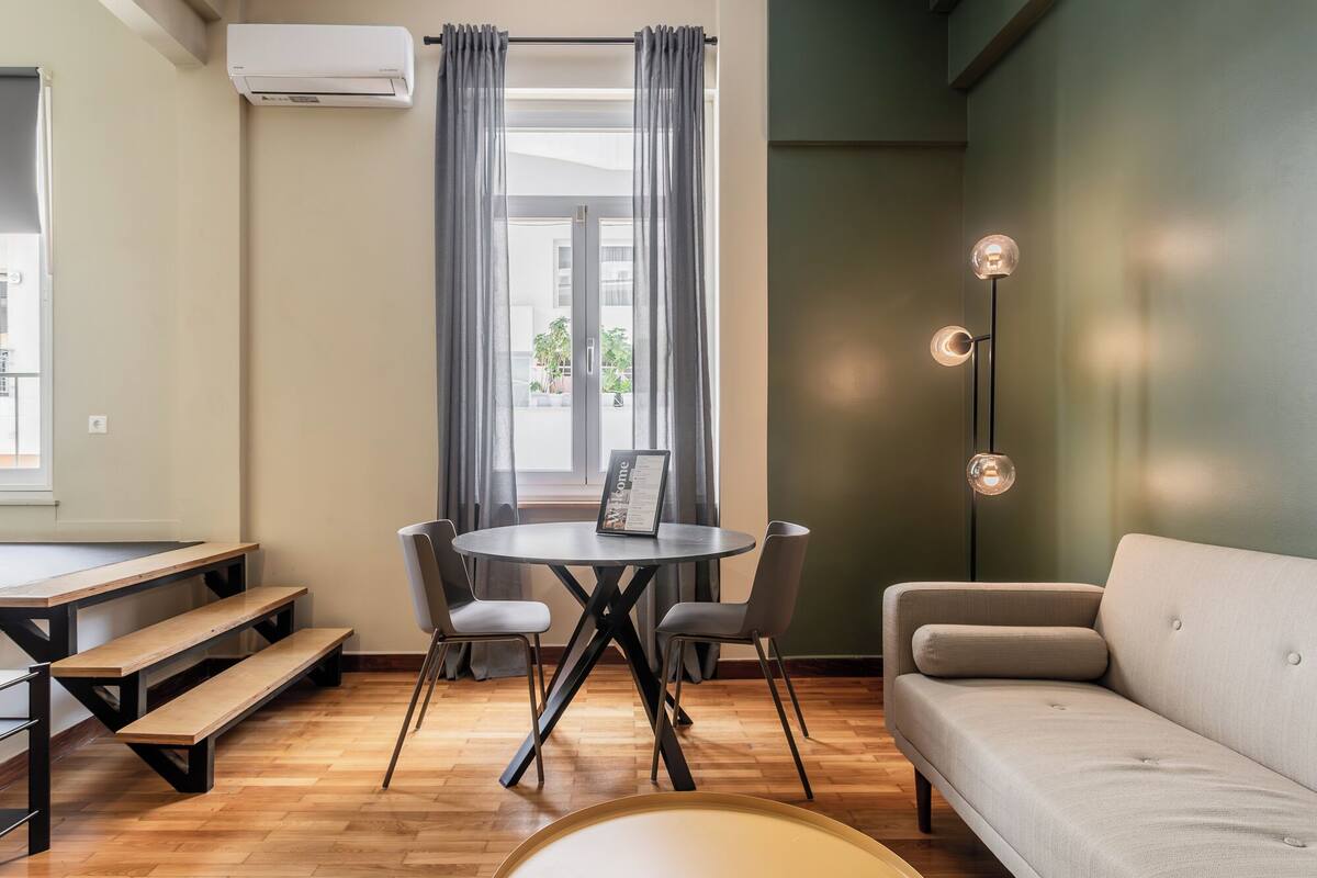 A modern living room with a round table, two chairs, a sofa, and a bench.