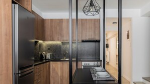 Cocina moderna con armarios de madera, un refrigerador de acero inoxidable, una estufa a gas y una zona de comedor con mesa lista para cuatro personas.