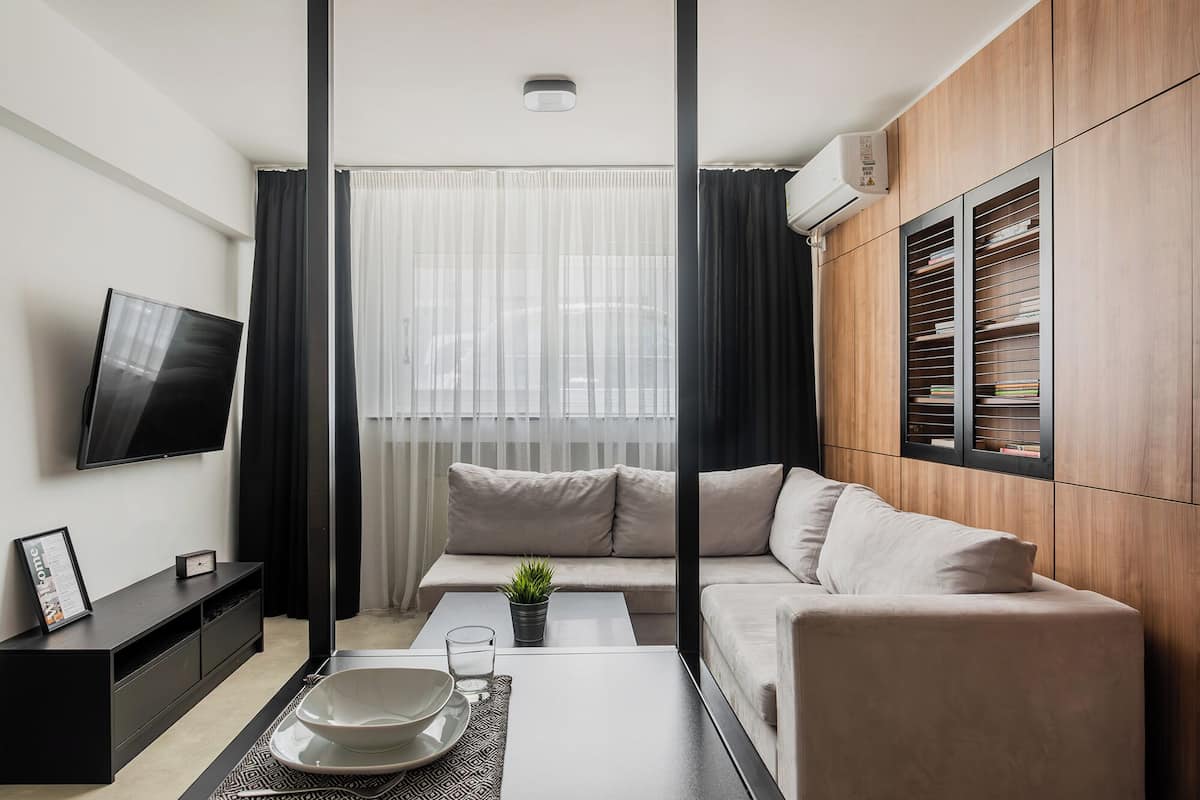 A modern living room with a sofa, a coffee table, a TV, and a built-in bookshelf.