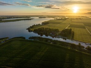 An aerial view of a river with surrounding fields and a small settlement. - Pean Huur je Eigen Schier Eiland (Nes)