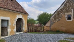 A rural building with a stone facade, an arched entrance, and a gravel driveway. - To complete (Berd'huis)