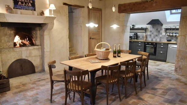 A rustic dining area with a fireplace, wooden table, and chairs. - To complete (Berd'huis)