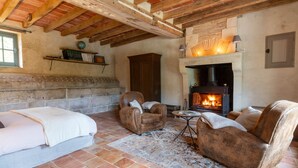 A rustic room with exposed wooden beams, a fireplace, leather sofas, and a stone wall. - To complete (Berd'huis)