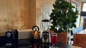 A kitchen with a Siemens toaster, a kettle, a blender, a red thermos, and a plant.