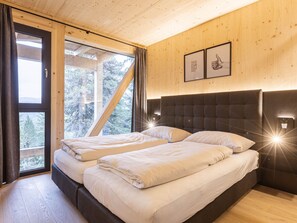 Une chambre avec deux lits, des murs en bois et une grande fenêtre avec des rideaux.