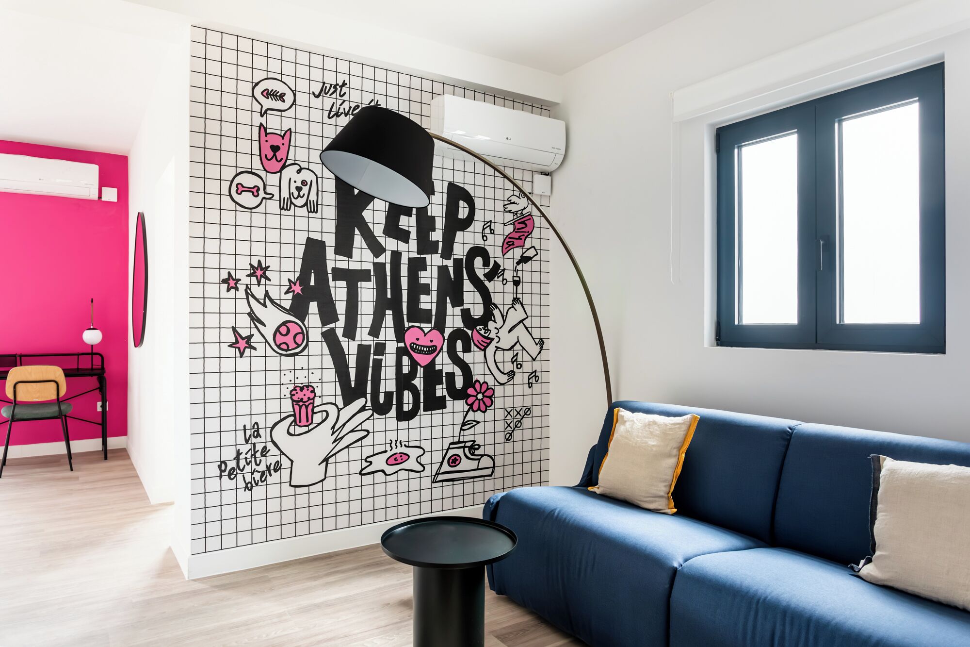 A room with a blue sofa, a black lamp, and a wall with a grid pattern and text.