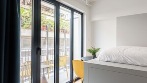 Quarto moderno com cama, uma mesinha e uma planta em vaso.