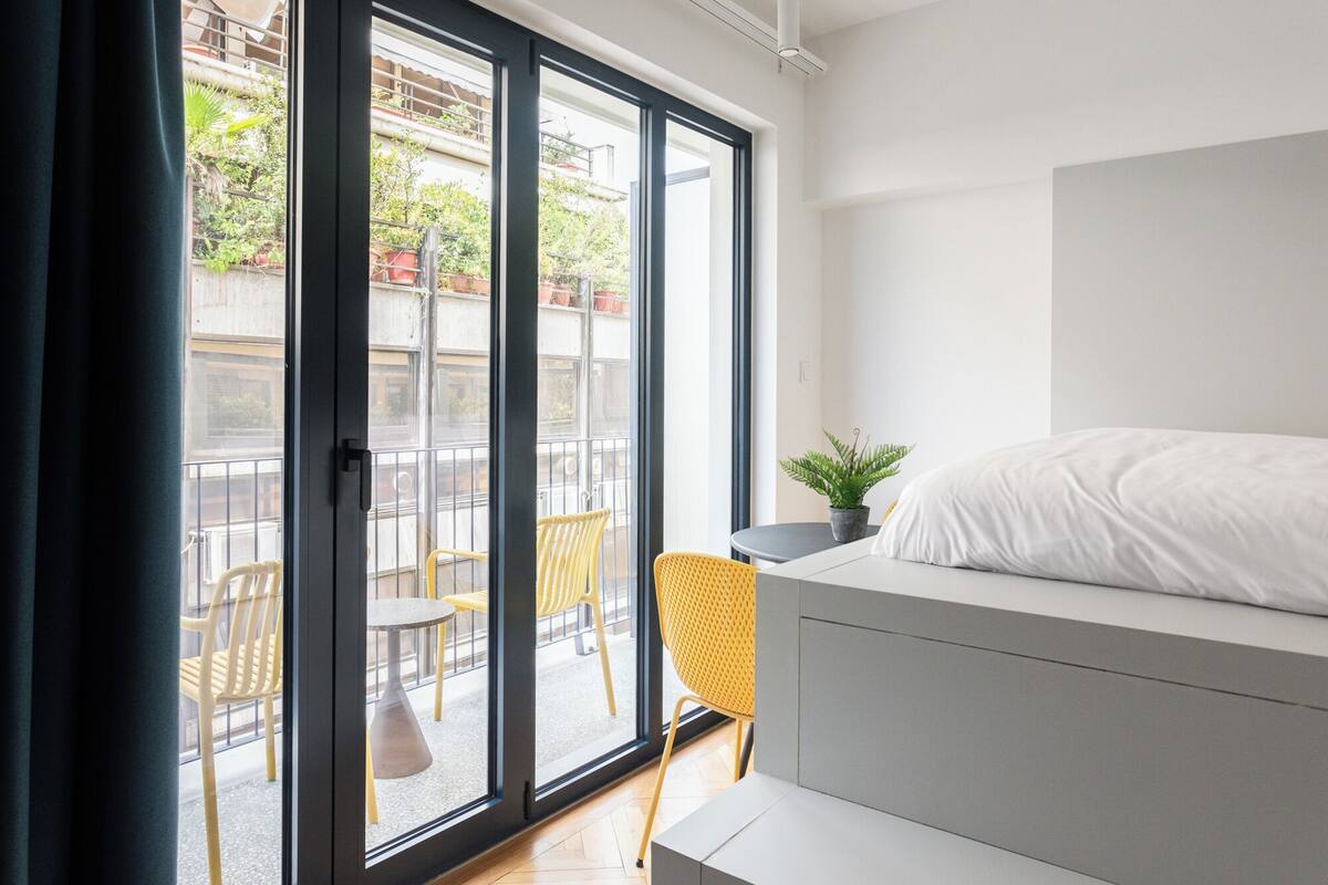 Un dormitorio moderno con una cama, una mesita y una planta en maceta.