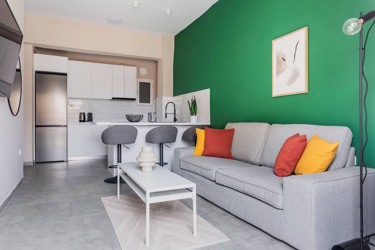 A modern living room with a grey sofa, a white coffee table, and a green accent wall.