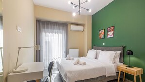 A modern bedroom with a bed, bedside table, chair, desk, and artwork on the wall. - Snug by Zoia Living (Athens)