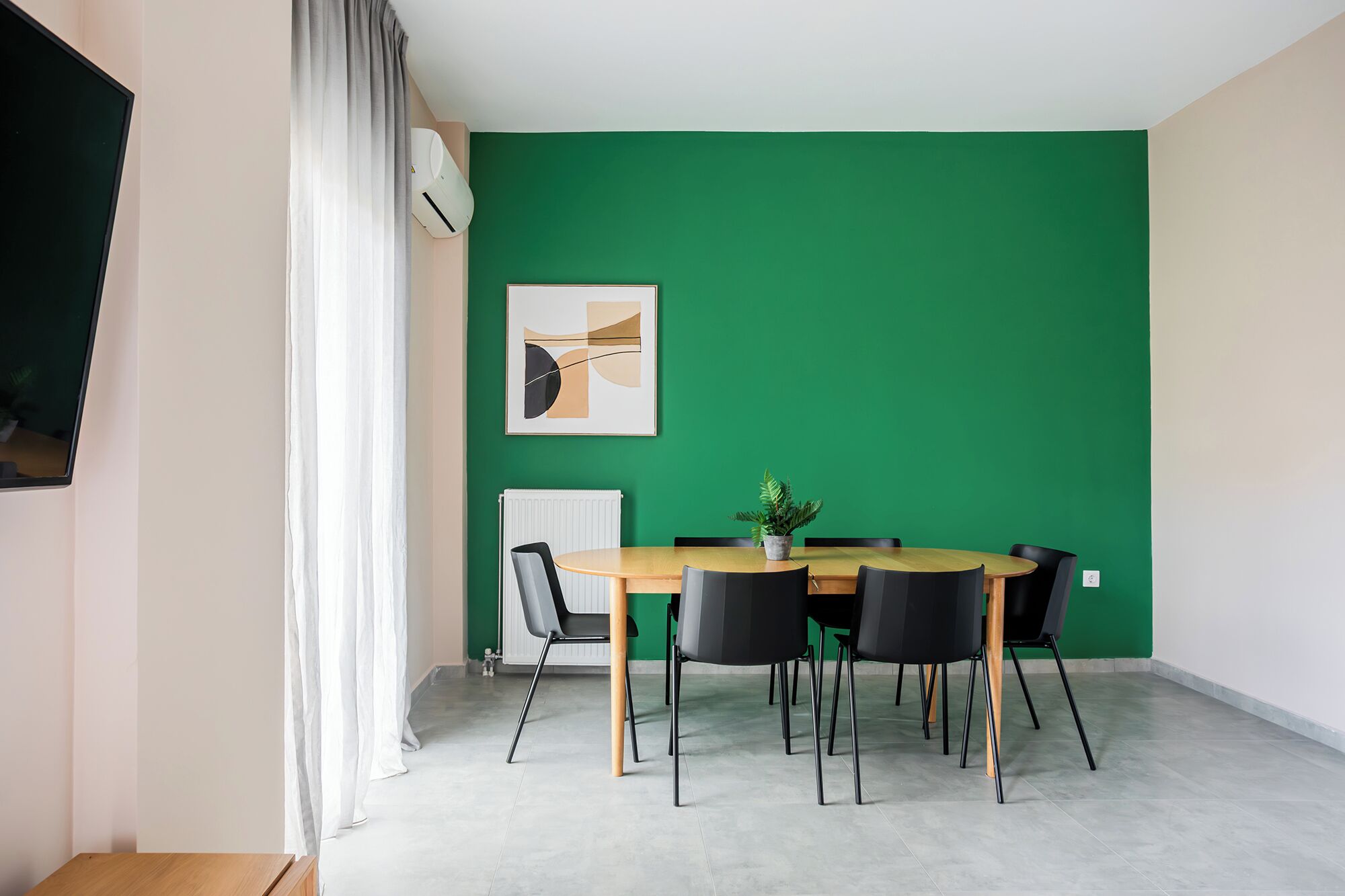 A conference room with a green wall, a round table, and six chairs.