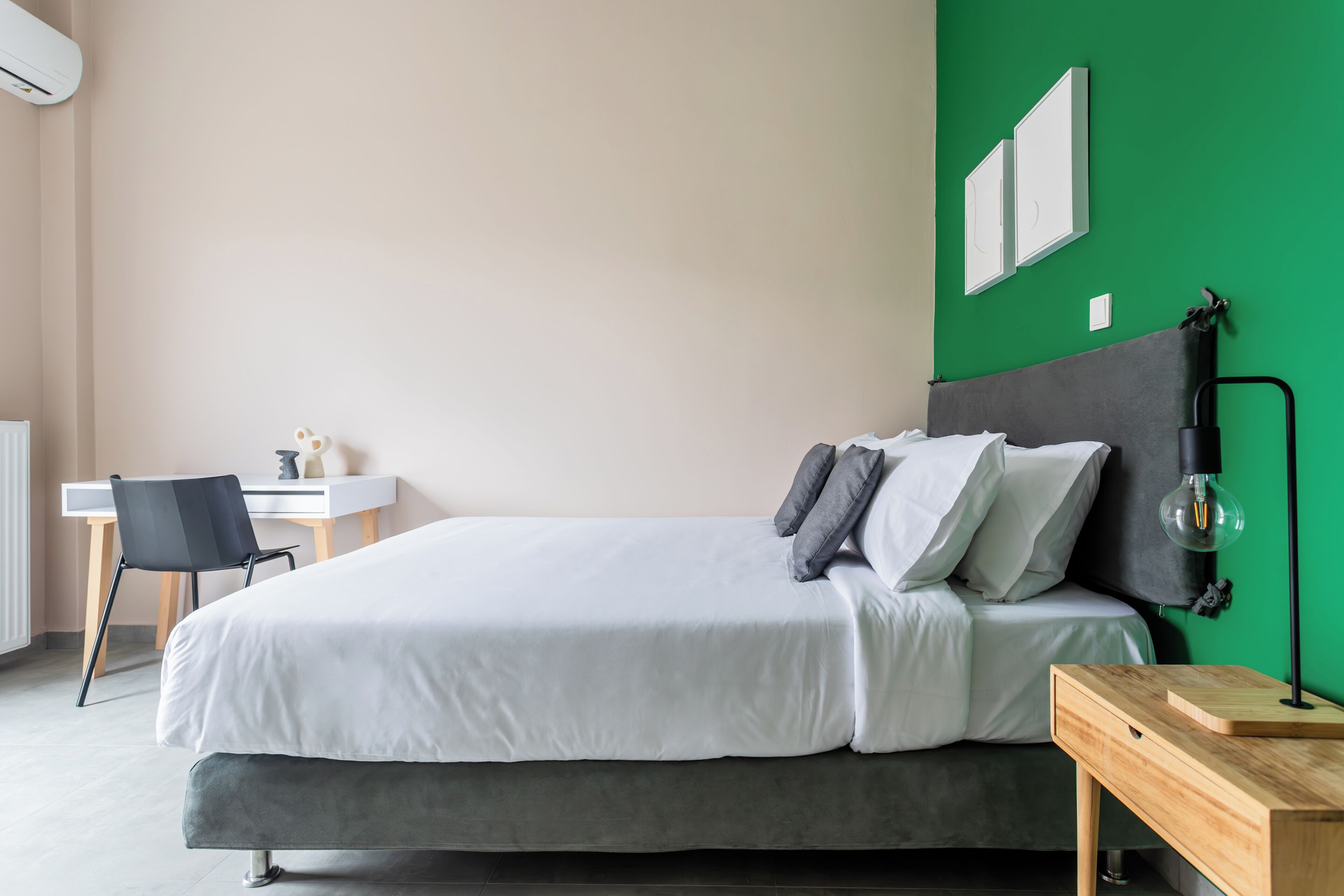 A neatly arranged bedroom with a bed, bedside table, and a desk with a chair.