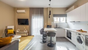 A modern kitchen with a dining area, a sofa, and a TV. - Snug by Zoia Living (Athens)