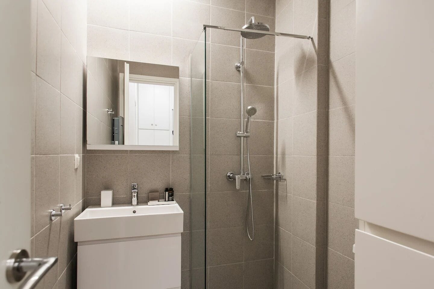 A modern bathroom with a glass-enclosed shower, a white sink, and a mirror above the sink.