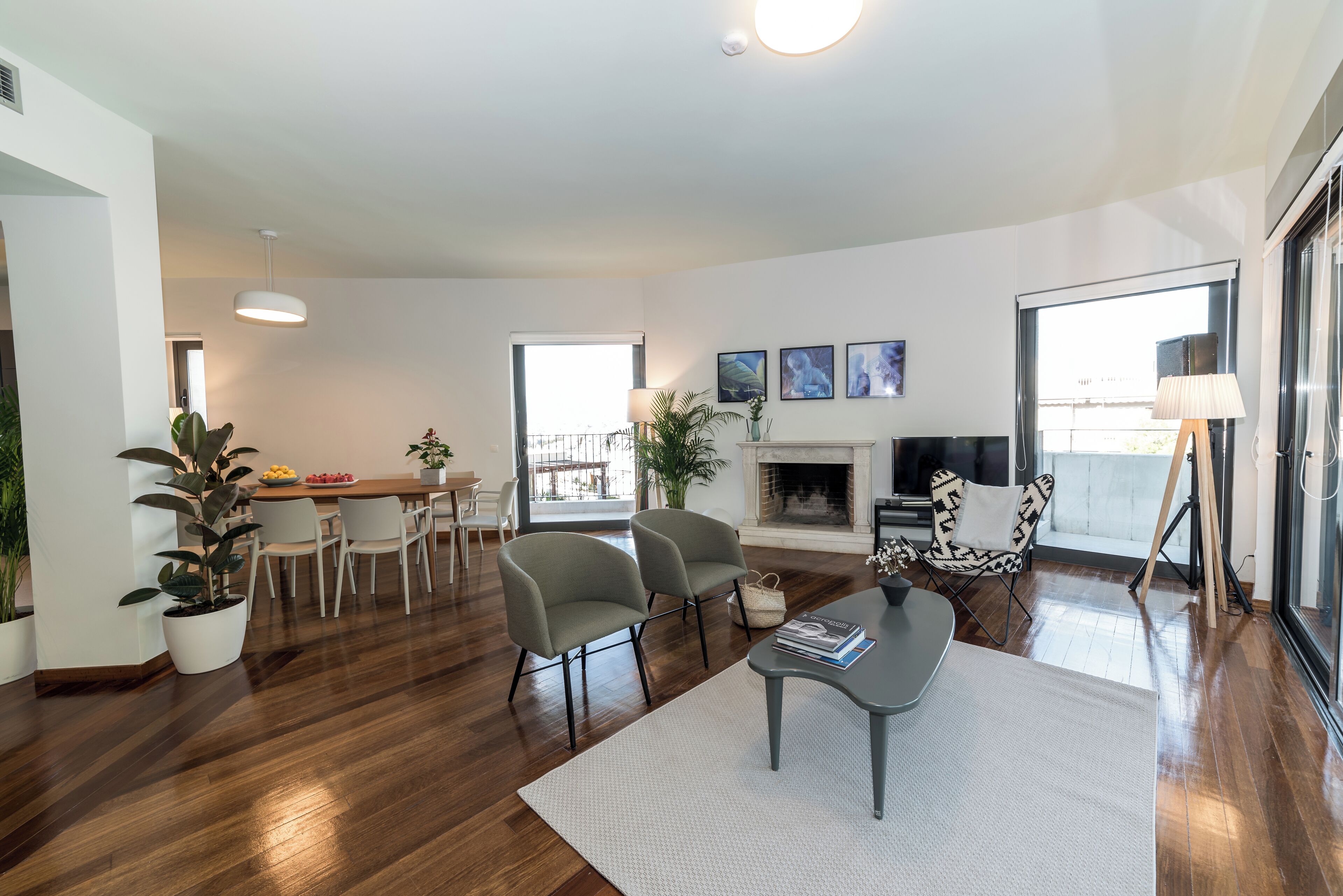 A modern living room with a fireplace, dining area, and large windows.