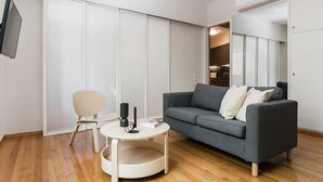 A modern living room with a grey sofa, a small round table, and a wooden floor. - The Hill by Zoia Living (Athens)
