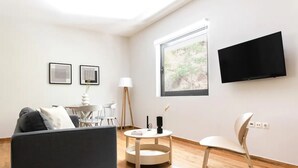 A modern living room with a sofa, a dining table, a TV, and a window with a view. - The Hill by Zoia Living (Athens)