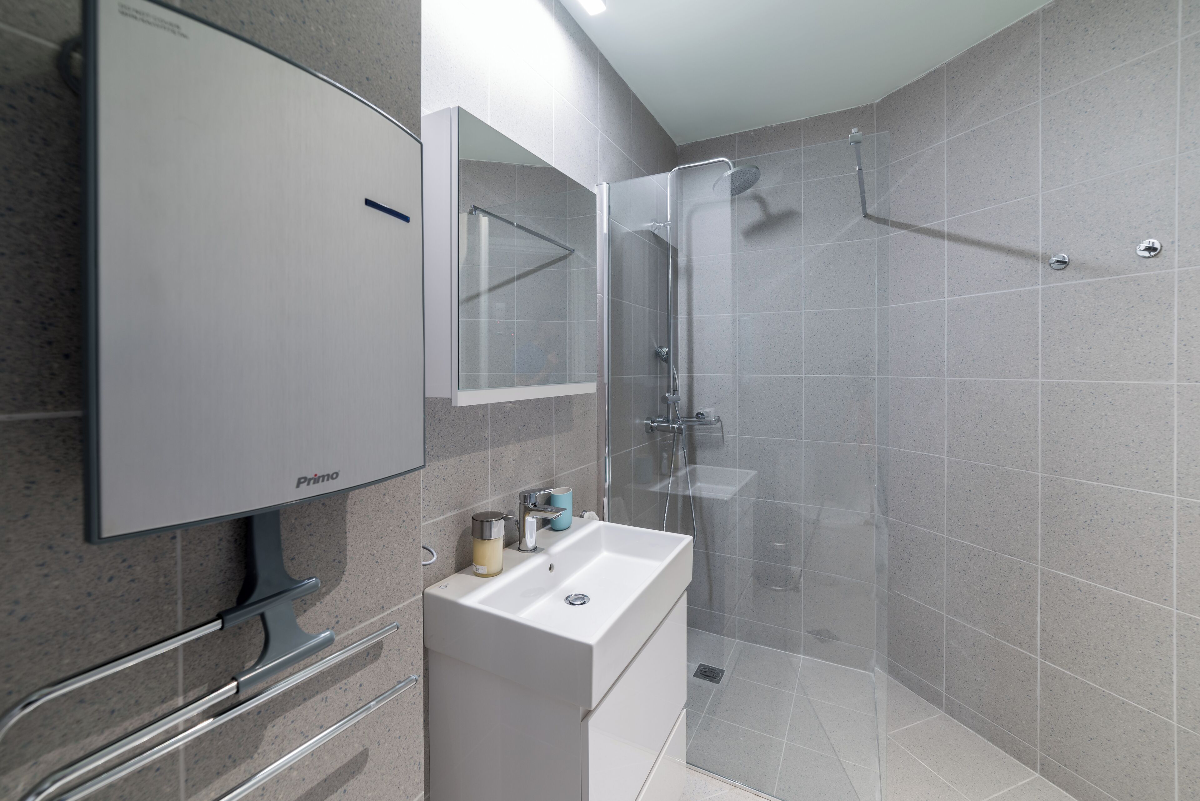 Une salle de bain moderne avec un grand miroir, un lavabo et un espace douche.