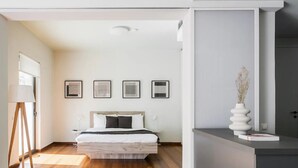 A modern bedroom with a large bed, a standing lamp, and framed artwork on the wall. - The Hill by Zoia Living (Athens)