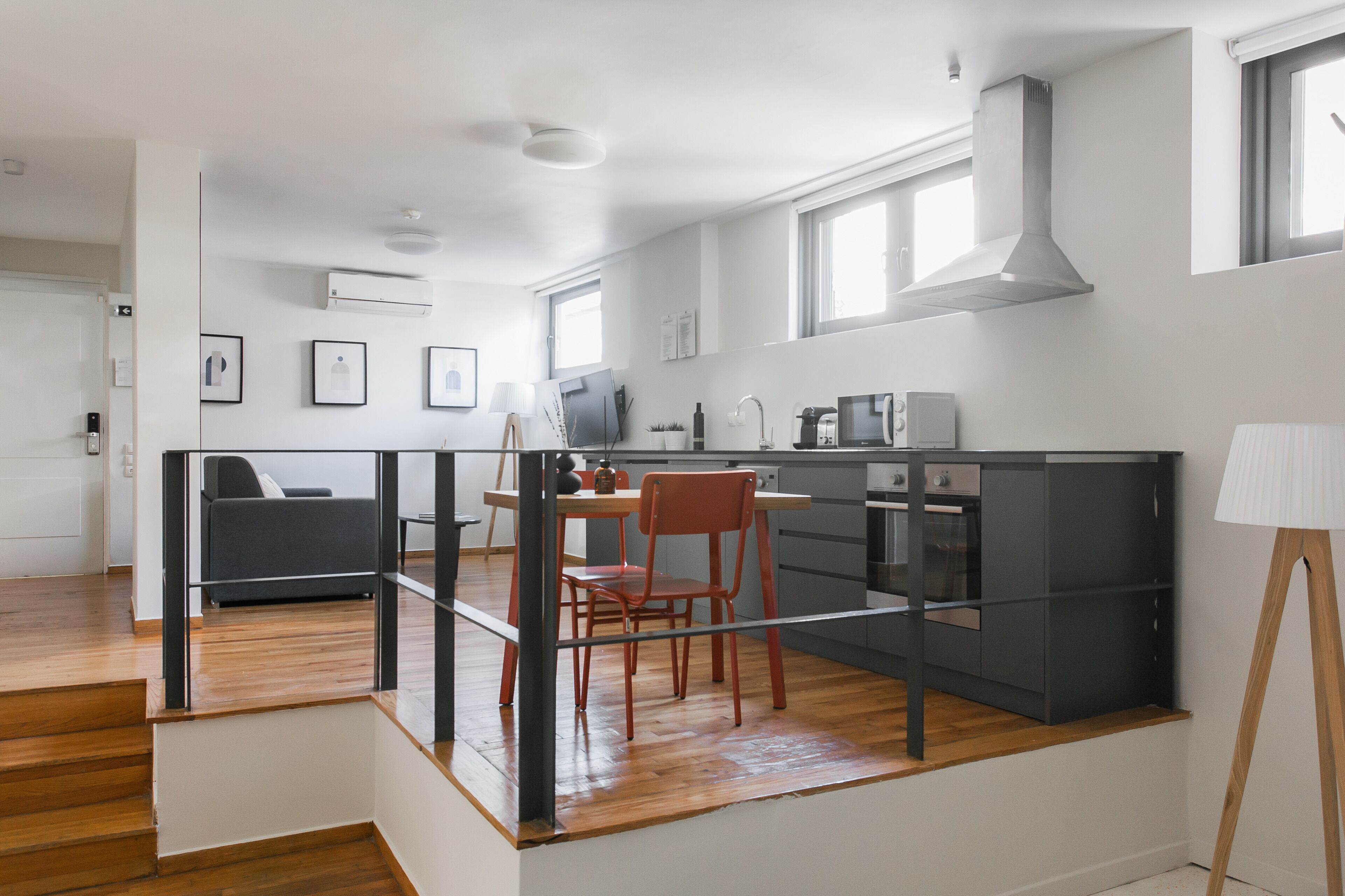 A modern kitchen with a dining area, wooden flooring, and a staircase leading to another level.