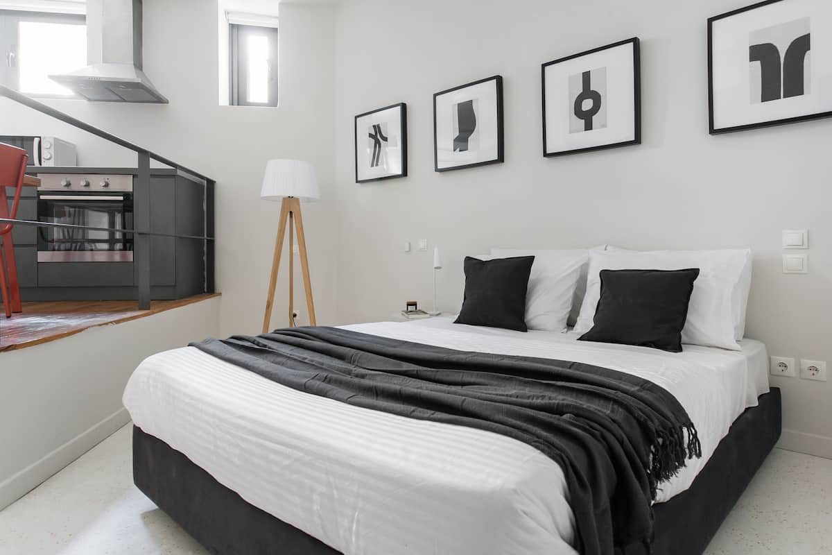 A bedroom with a bed, a bedside table, a lamp, and a wall-mounted artwork.