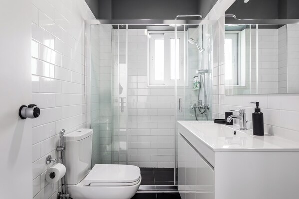 A modern bathroom with a toilet, shower, and sink. - OneZeroTwo by Zoia Living (Athens)