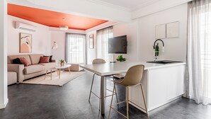 A modern living room with a sofa, coffee table, and dining area. - OneZeroTwo by Zoia Living (Athens)
