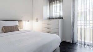 A bedroom with a bed, a wardrobe, and a window with sheer curtains. - OneZeroTwo by Zoia Living (Athens)
