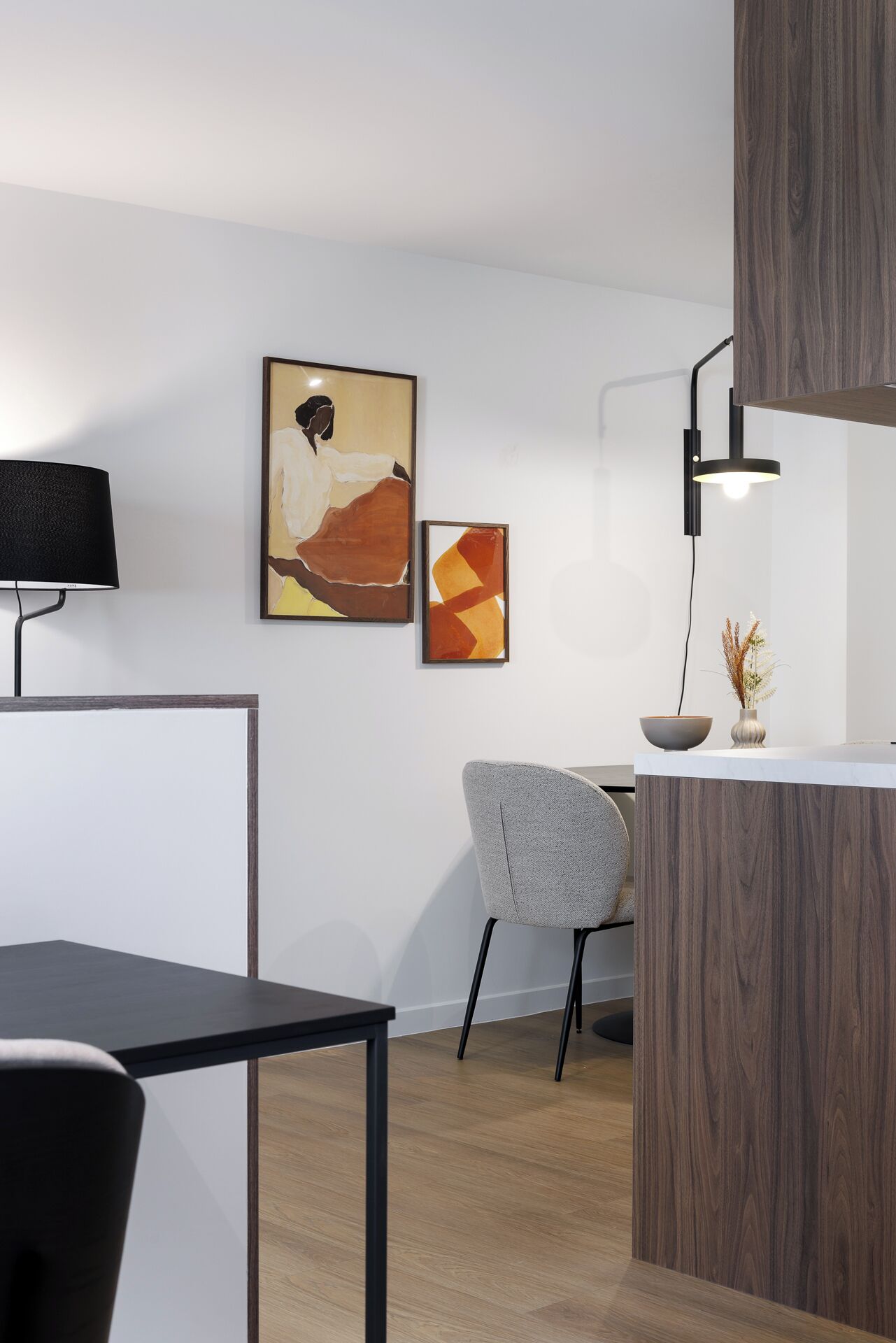 A modern office space with a desk, chair, and two abstract paintings on the wall.