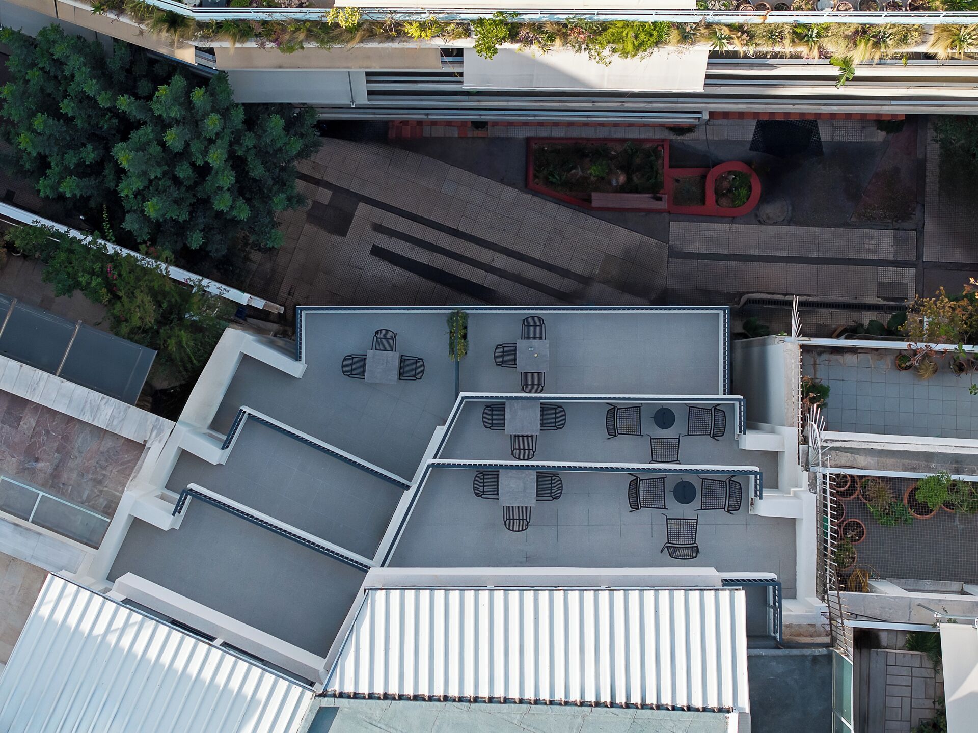 An aerial view of a rooftop terrace with multiple seating areas and a small garden.