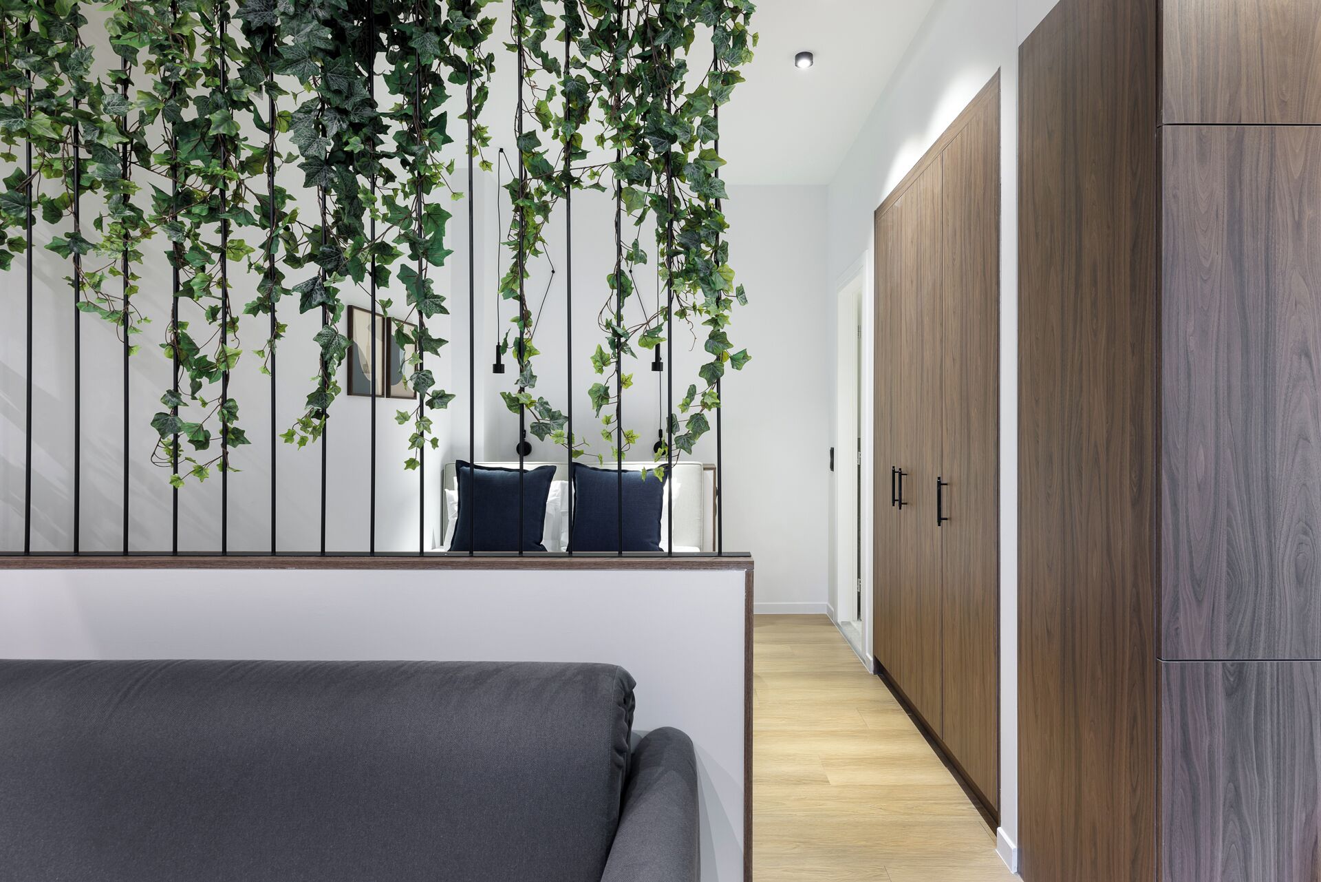 A modern bedroom with a bed, a wooden wardrobe, and a wall-mounted plant installation.